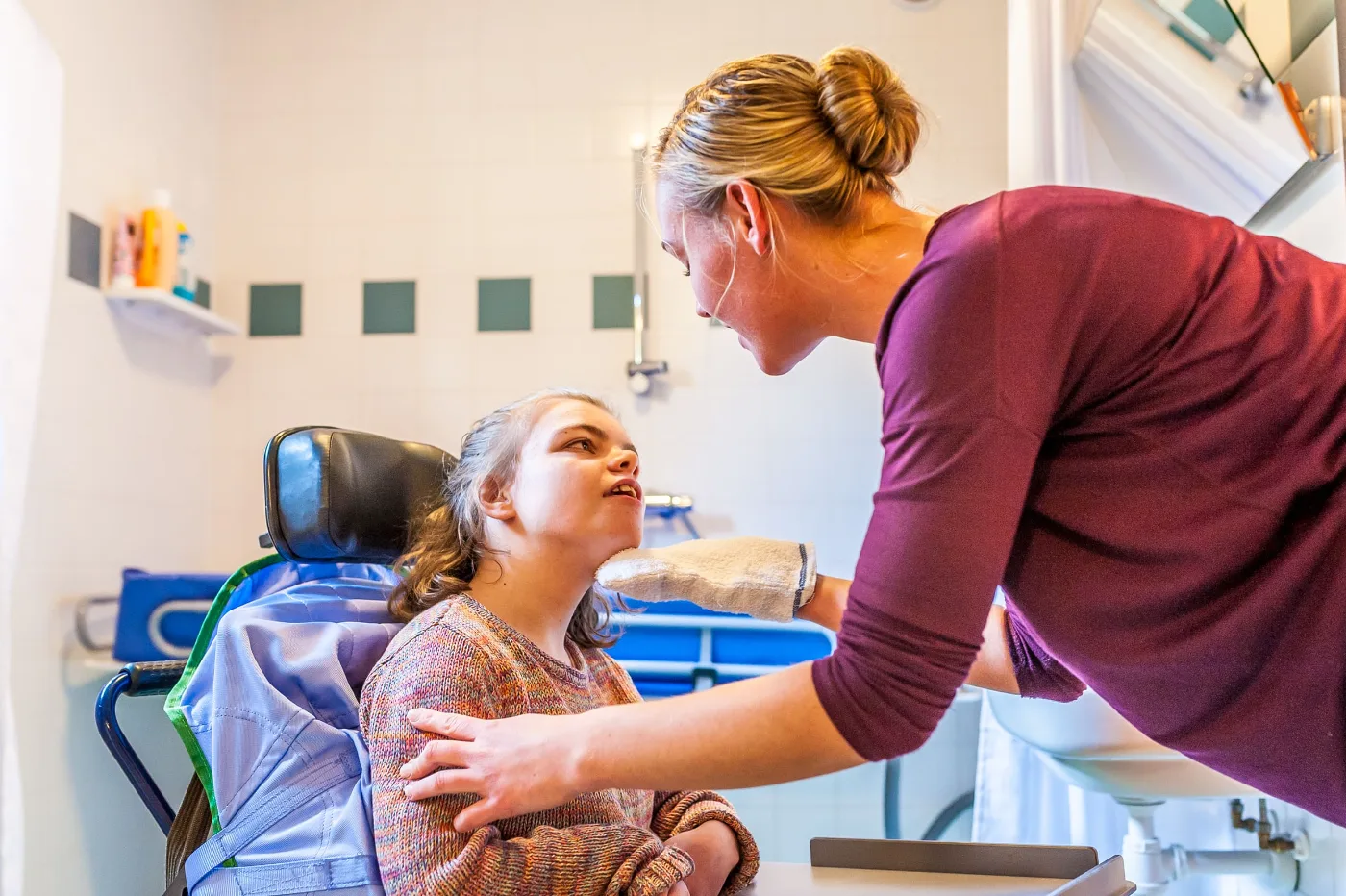 Support worker assisting a young participant with personal care in an accessible bathroom