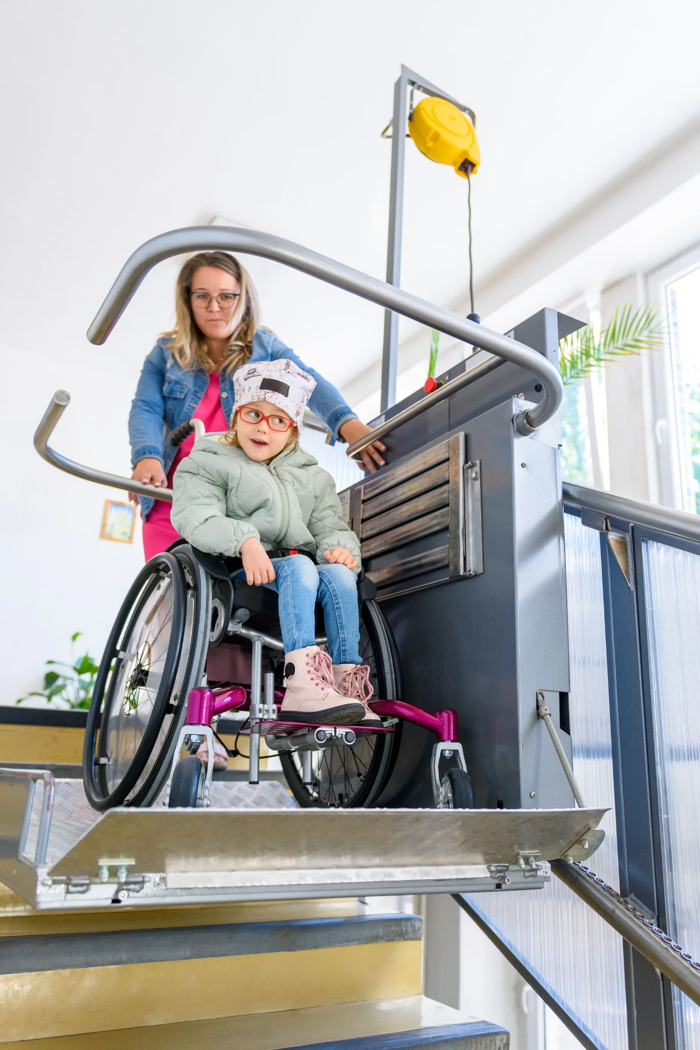Child in a wheelchair using an accessible platform lift with a support worker