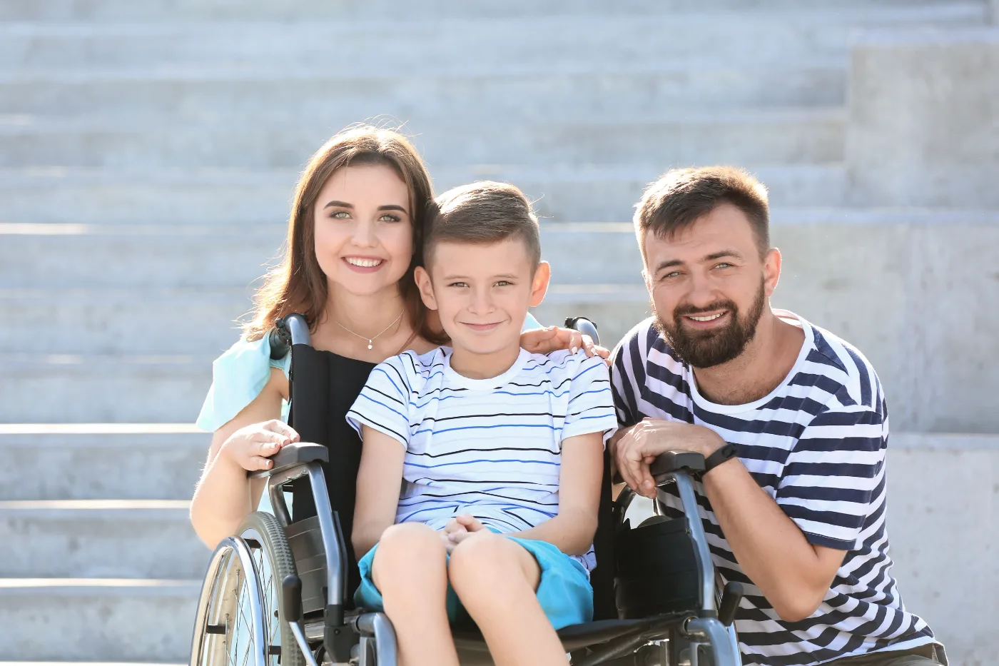 Parents with their son, who uses a wheelchair, smiling outdoors in Melbourne